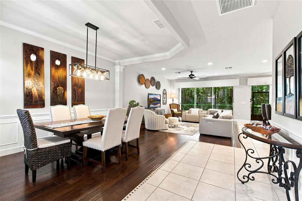 An open-concept dining and living area features dark wood floors, tile flooring, and neutral furniture — 1411 LISBON CT, DAVENPORT, FL