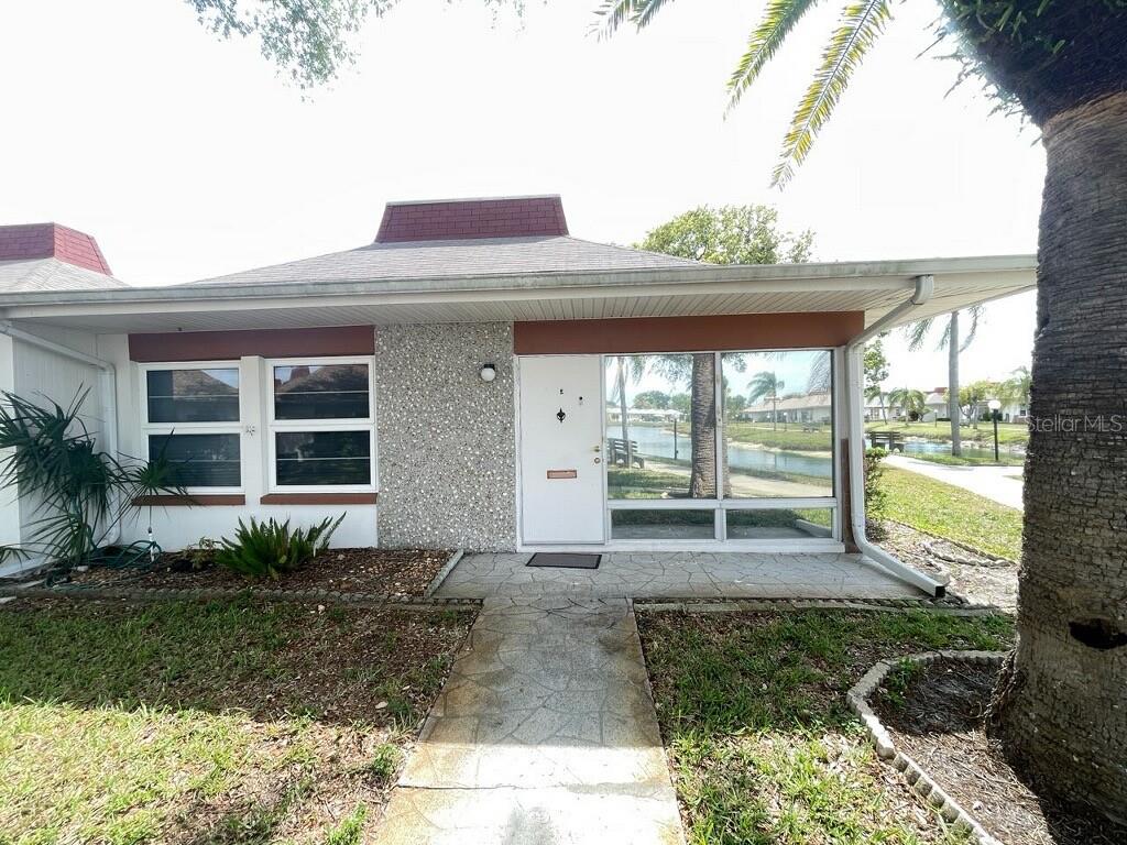 A single-story building with white stucco walls, a stone facade, and a hip roof — 4326 TAHITIAN GARDENS CIRCLE UNIT 14E, HOLIDAY, FL