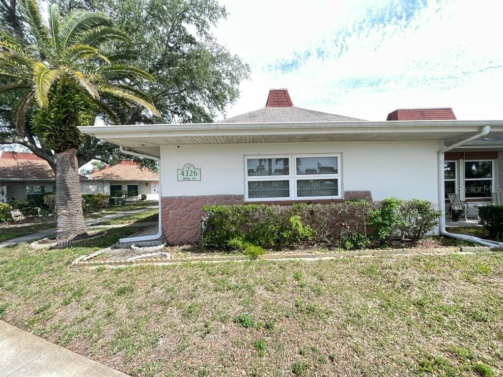 A paved walkway leads past a small pond and palm trees toward residential buildings — 4326 TAHITIAN GARDENS CIRCLE UNIT 14E, HOLIDAY, FL