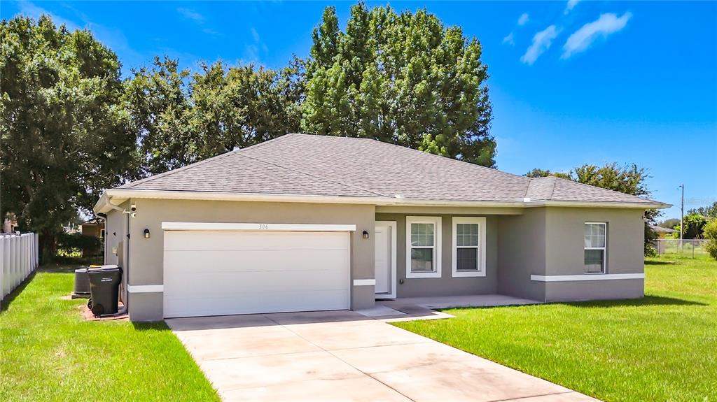 A single-story house with a gray exterior, a two-car garage, and a concrete driveway — 306 CLEARWATER LANE, POINCIANA, FL
