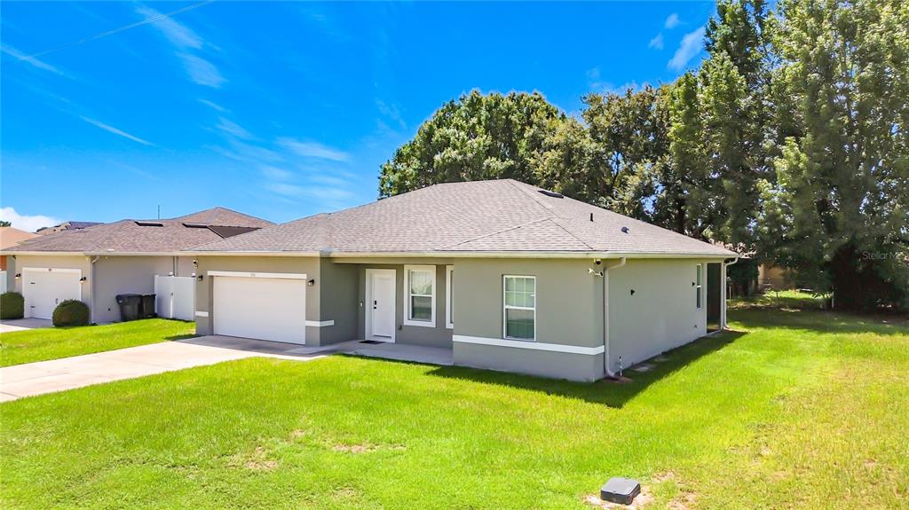 A single-story house with a gray stucco exterior, a two-car garage, and a shingled roof — 306 CLEARWATER LANE, POINCIANA, FL