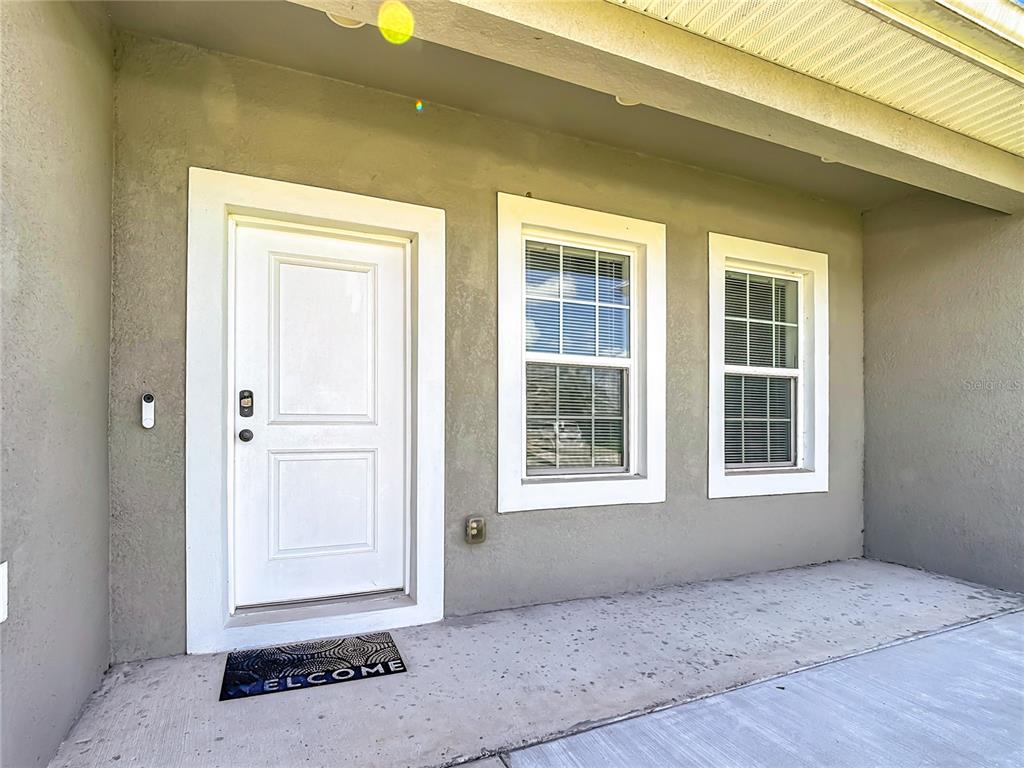 A white front door and two windows are set into a beige exterior wall — 306 CLEARWATER LANE, POINCIANA, FL