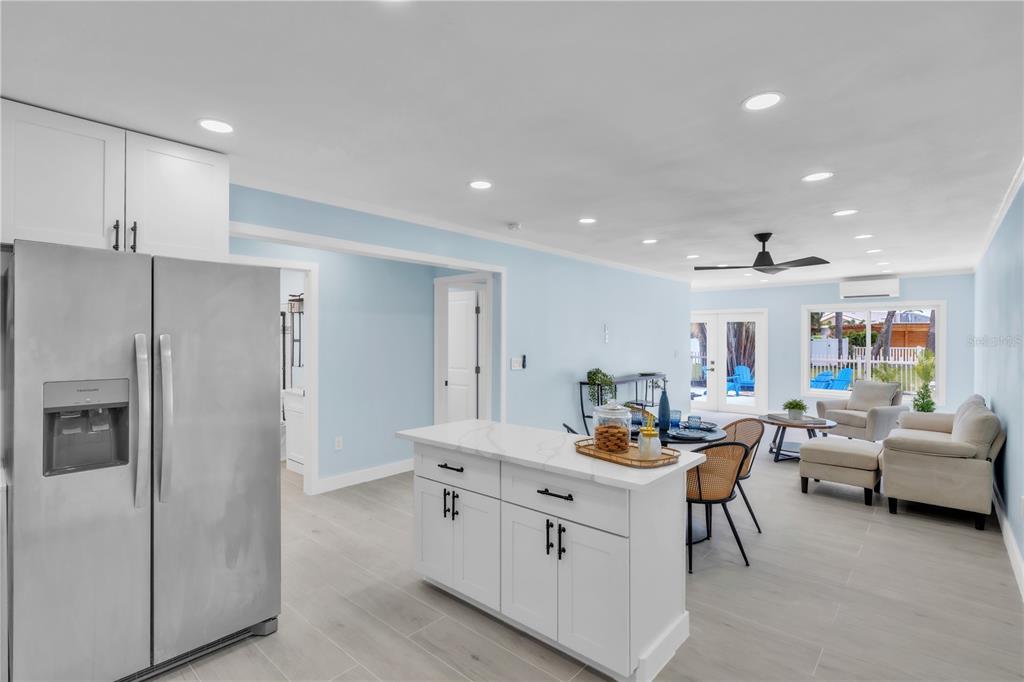 A modern kitchen features white cabinets, stainless steel appliances, gray tile backsplash, and a central island — 445 63RD STREET, HOLMES BEACH, FL