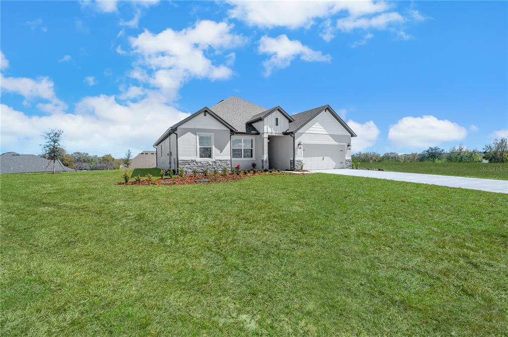 A single-story house with a white exterior, stone accents, and a two-car garage — 3849 SADDLE HILL TRAIL, FRUITLAND PARK, FL