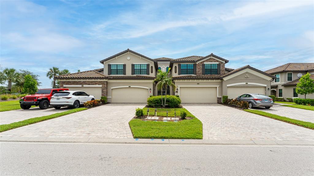 A two-story multi-family home with four garage doors and a paved driveway — 5805 WAKE FOREST RUN UNIT 103, LAKEWOOD RANCH, FL