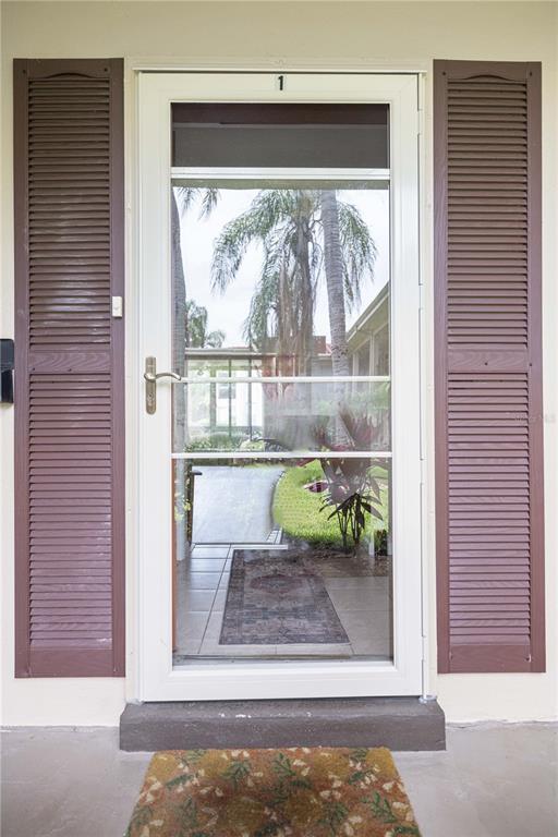 A white storm door with a number one sits between two brown louvered shutters — 19029 US HIGHWAY 19 N UNIT 3-1, CLEARWATER, FL