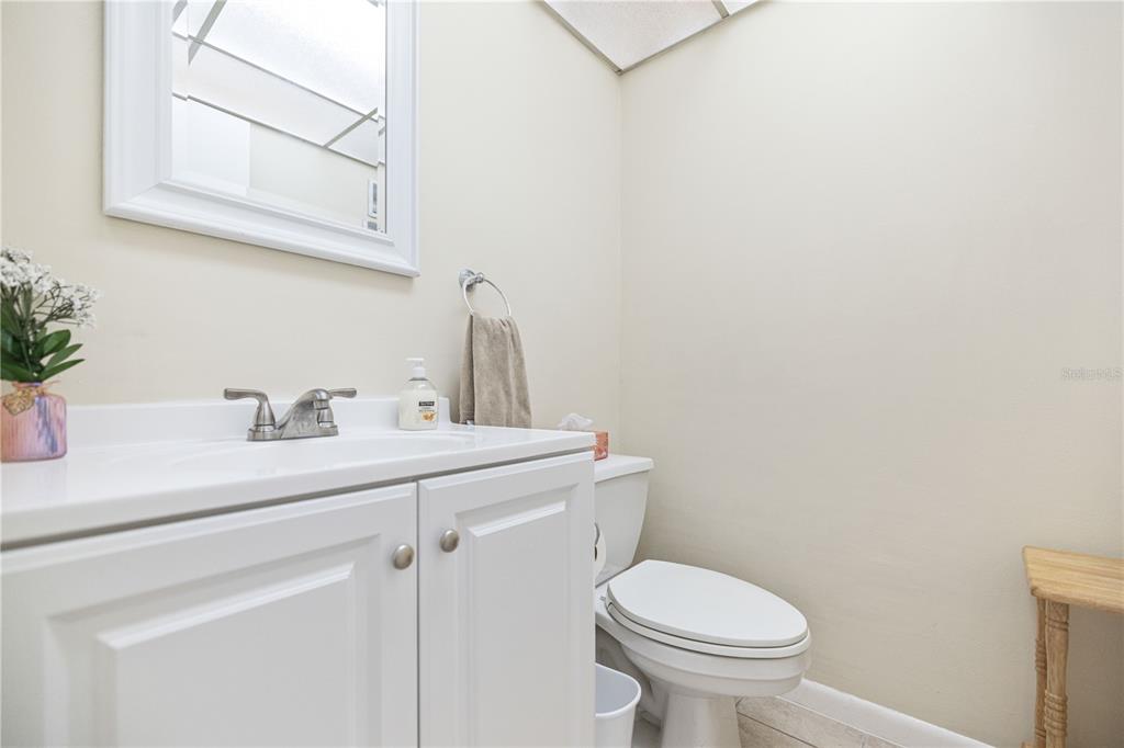 A small bathroom features a white vanity, a mirror, and a toilet — 19029 US HIGHWAY 19 N UNIT 3-1, CLEARWATER, FL