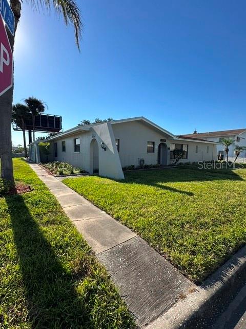 A light-colored, single-story house features a prominent angled architectural element and a concrete walkway — 2301 W BAY DRIVE, LARGO, FL