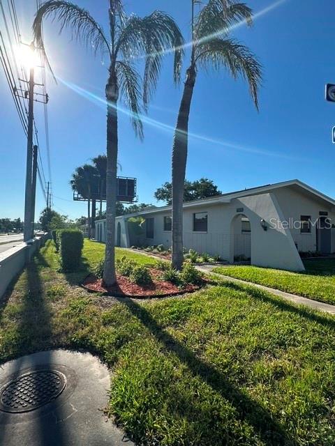 A low-slung, light-colored building sits behind two tall palm trees near a roadside billboard — 2301 W BAY DRIVE, LARGO, FL