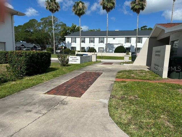 A concrete driveway with a brick inlay leads toward a multi-story apartment building — 2301 W BAY DRIVE, LARGO, FL