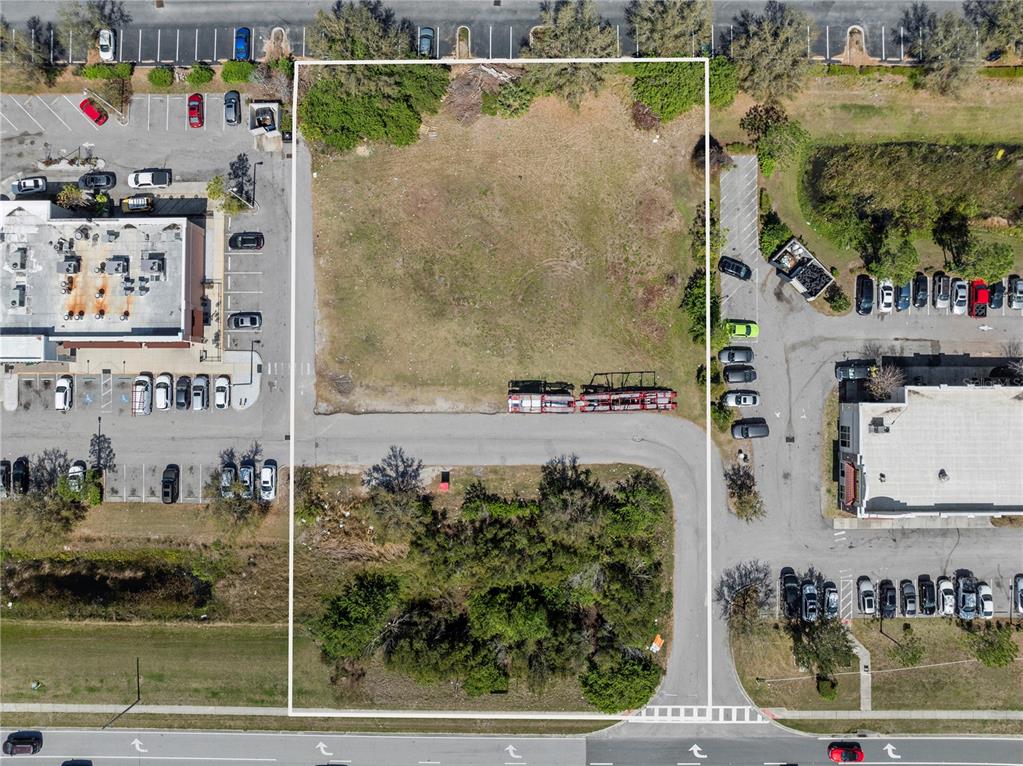 An aerial view shows a vacant, rectangular plot of land surrounded by paved parking lots — BIG BEND ROAD, RIVERVIEW, FL