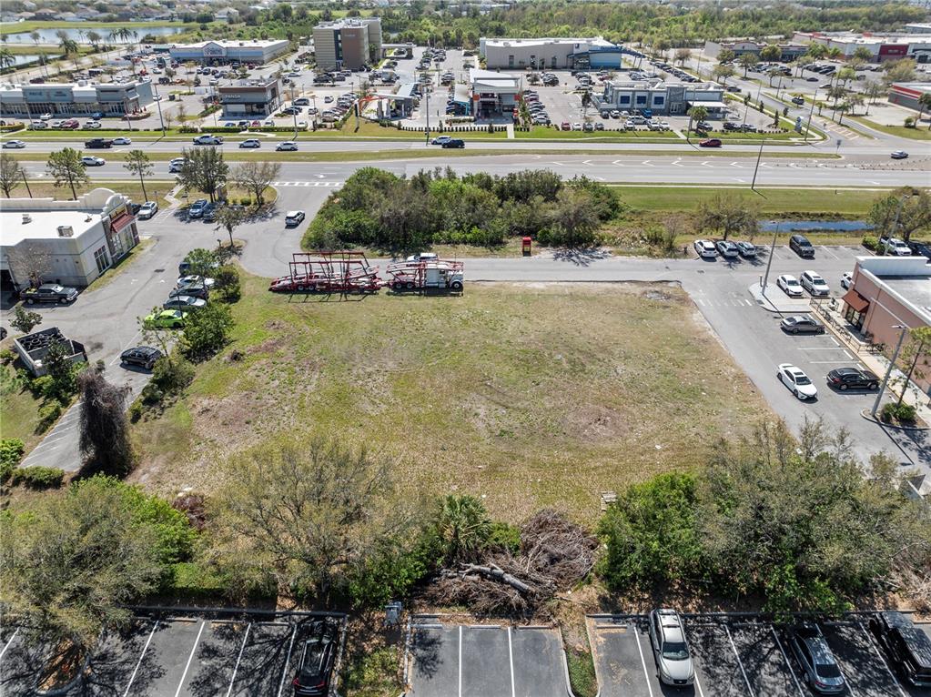 An aerial view shows a vacant, grassy lot surrounded by parking lots and commercial buildings — BIG BEND ROAD, RIVERVIEW, FL
