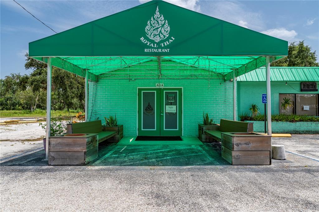 The exterior of a green brick restaurant building features a large matching green fabric awning — 4214 DUNCAN ROAD, PUNTA GORDA, FL