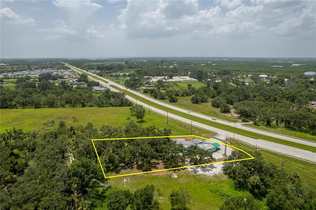 An aerial view shows a commercial building on a wooded lot adjacent to a highway — 4214 DUNCAN ROAD, PUNTA GORDA, FL