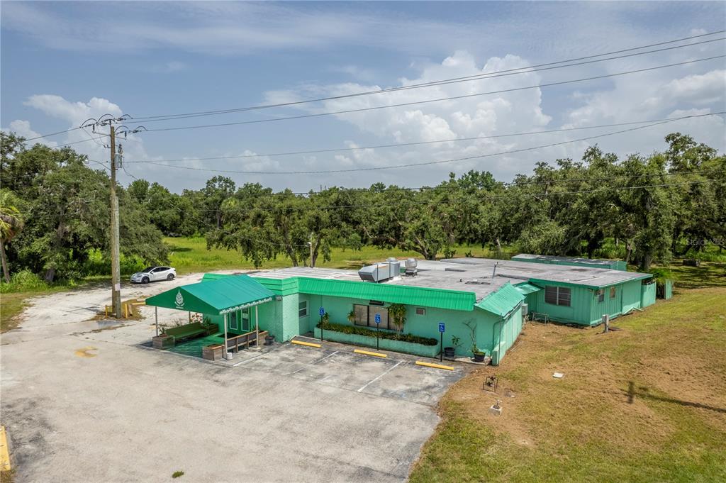 An aerial view of a single-story green commercial building with a metal awning and parking — 4214 DUNCAN ROAD, PUNTA GORDA, FL