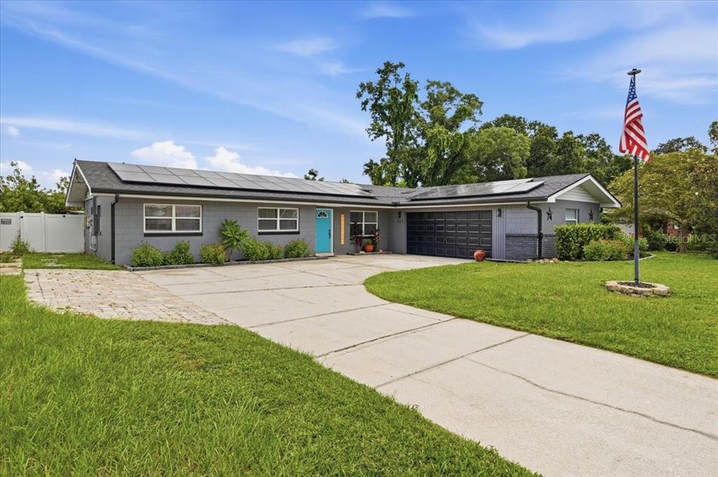 A gray single-story house with a blue front door, solar panels, and a concrete driveway — 121 LOWELL ROAD, WINTER HAVEN, FL