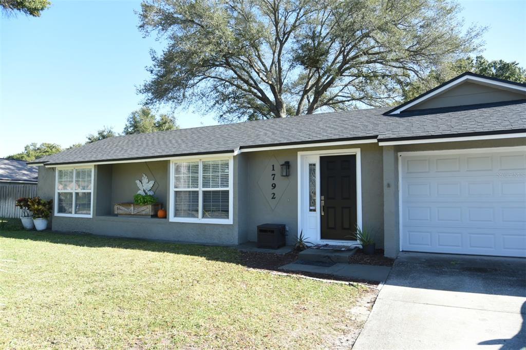 A single-story house with a gray exterior, dark front door, and a white garage door — 1792 PAM CIRCLE, BELLE ISLE, FL