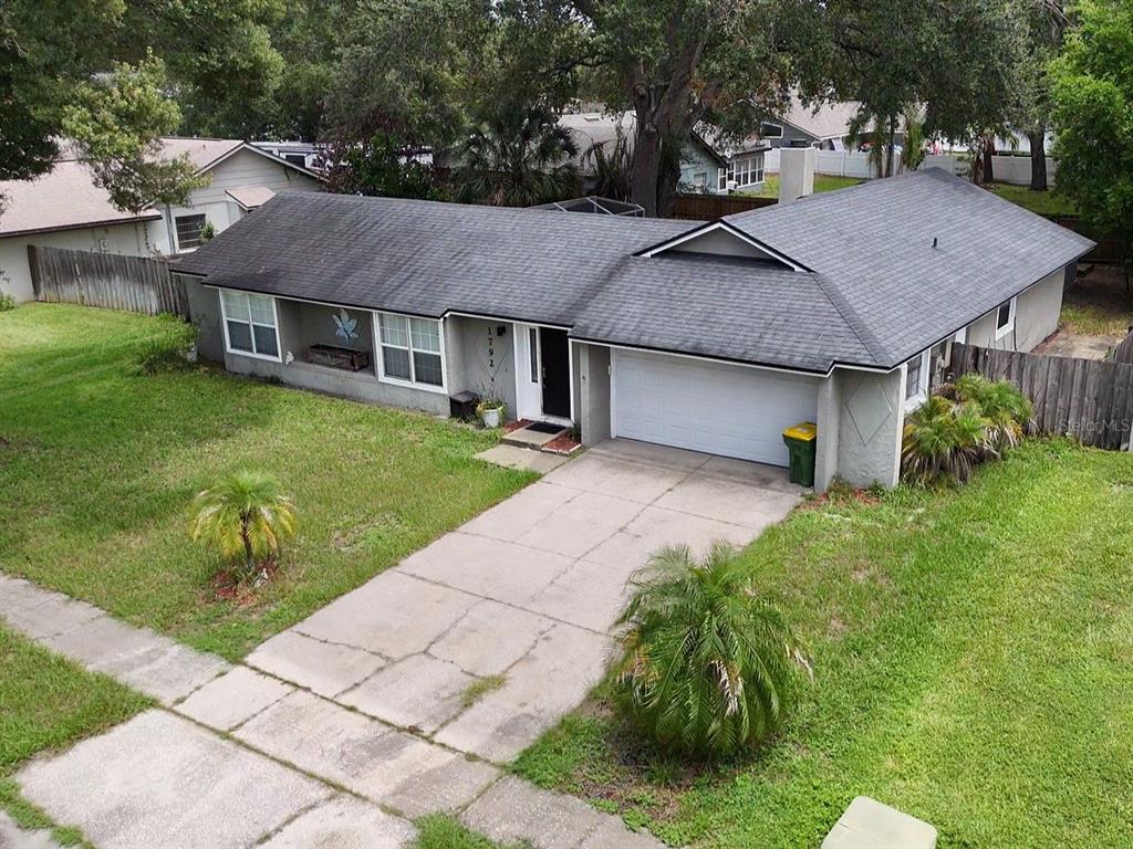 An aerial view of a single-story house with a gray shingled roof and concrete driveway — 1792 PAM CIRCLE, BELLE ISLE, FL