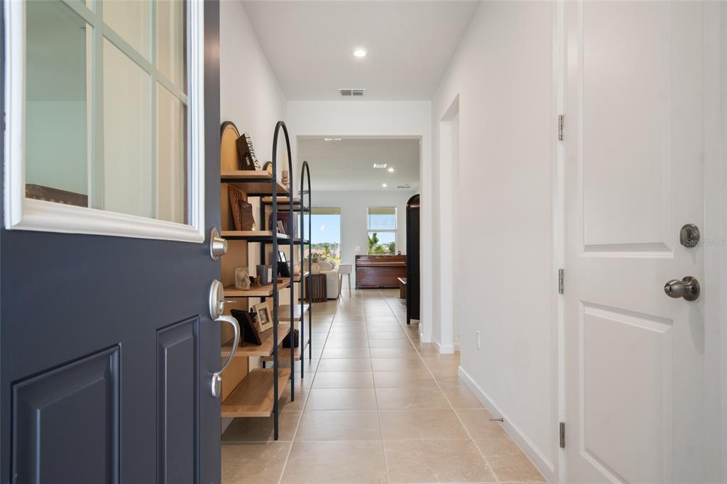 A view from an open front door into a tiled hallway with a metal shelving unit — 2685 SWEET ACACIA DRIVE, CLERMONT, FL