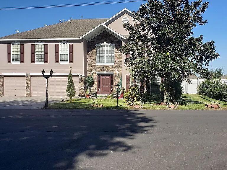 A two-story house with a stone facade, brown shutters, and a large tree in front — 959 THOMAS ROAD, EAGLE LAKE, FL
