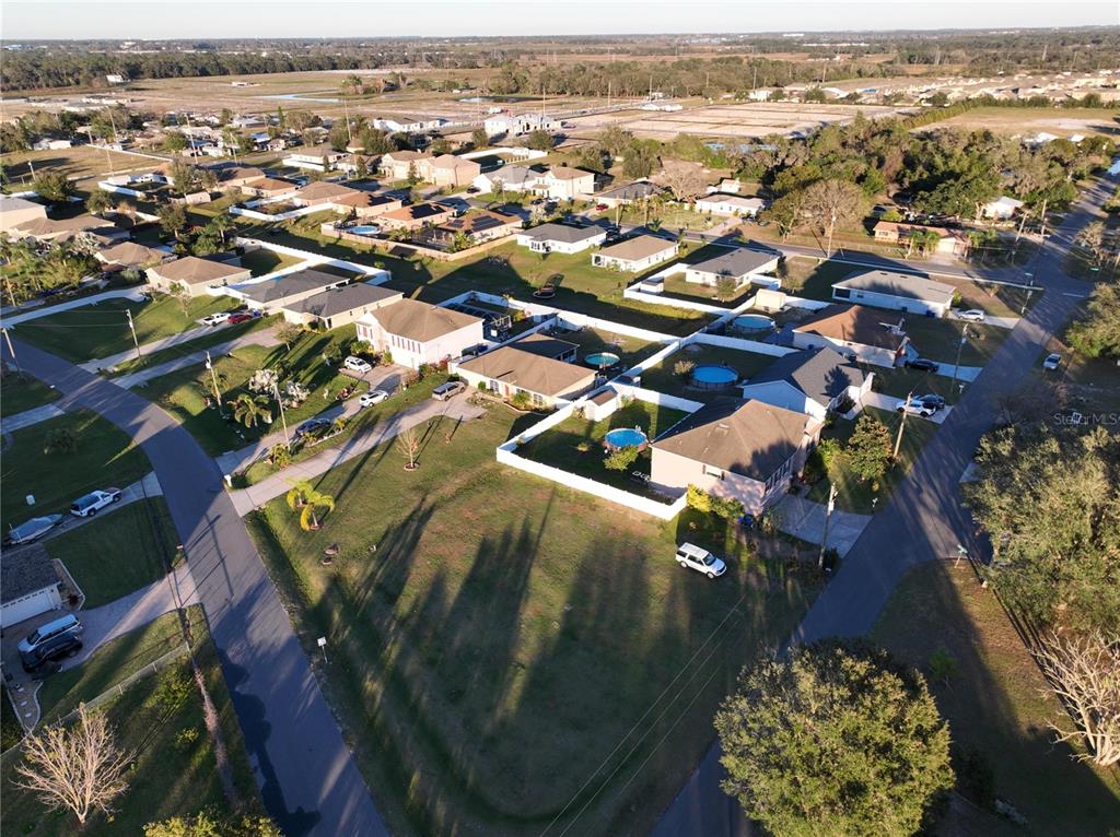 An aerial view shows a suburban neighborhood with houses, swimming pools, and paved streets — 959 THOMAS ROAD, EAGLE LAKE, FL