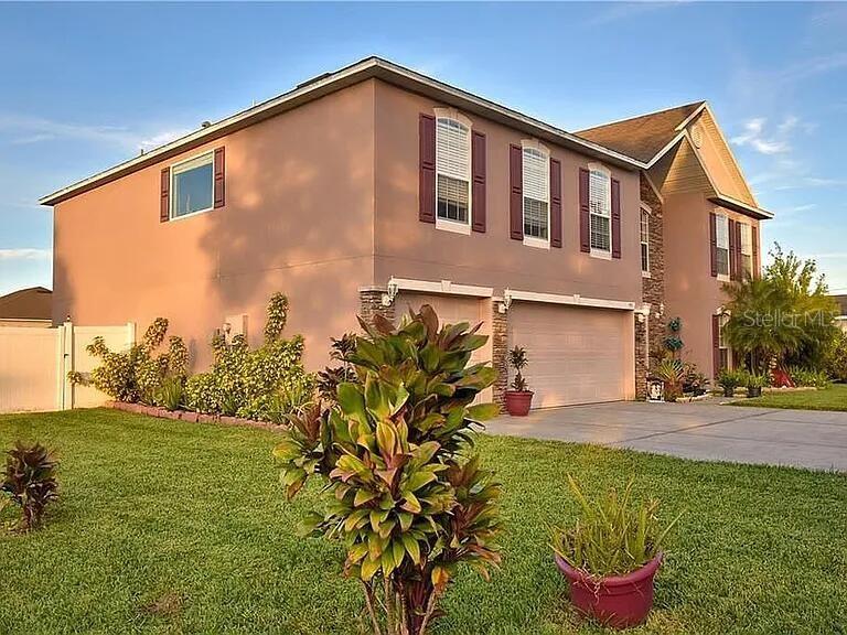 A two-story stucco house features a two-car garage and a landscaped front yard — 959 THOMAS ROAD, EAGLE LAKE, FL