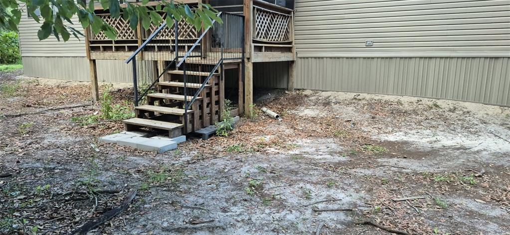 A wooden staircase with metal railings leads up to a deck attached to a house — 933 NE FIR ST, PINETTA, FL