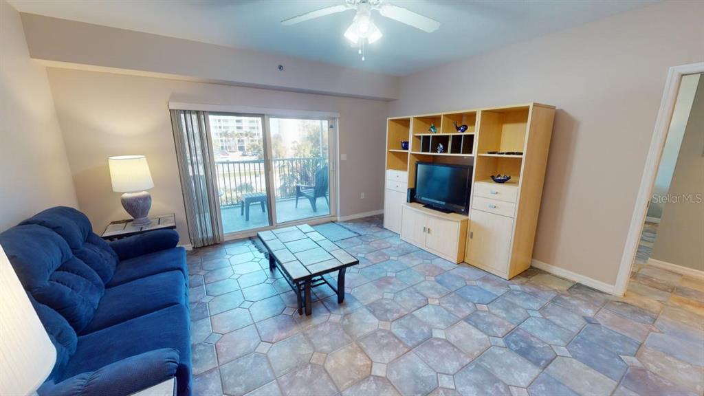 A living room features a blue sofa, tile flooring, a media center, and a balcony — 5300 S ATLANTIC AVENUE UNIT 2-303, NEW SMYRNA BEACH, FL