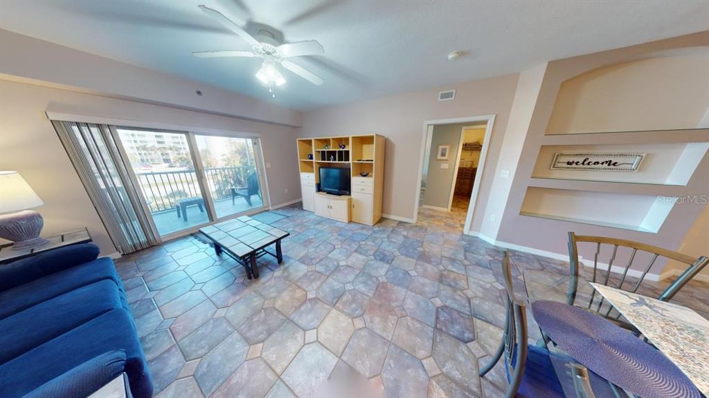 A living room with tile flooring, a ceiling fan, a balcony, and built-in wall shelving — 5300 S ATLANTIC AVENUE UNIT 2-303, NEW SMYRNA BEACH, FL