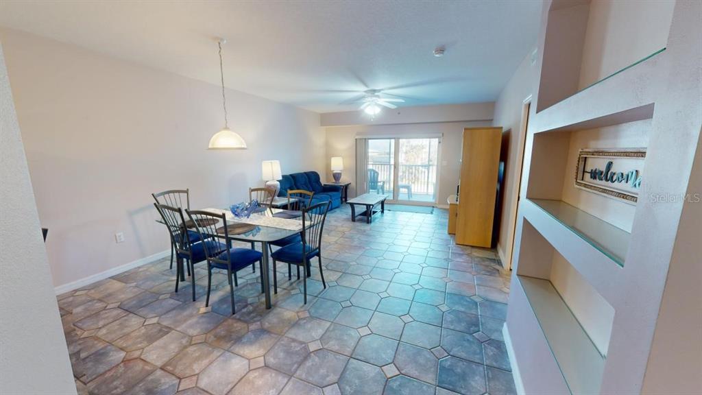 An open-concept living and dining area features tile flooring, a glass dining table, and balcony access — 5300 S ATLANTIC AVENUE UNIT 2-303, NEW SMYRNA BEACH, FL