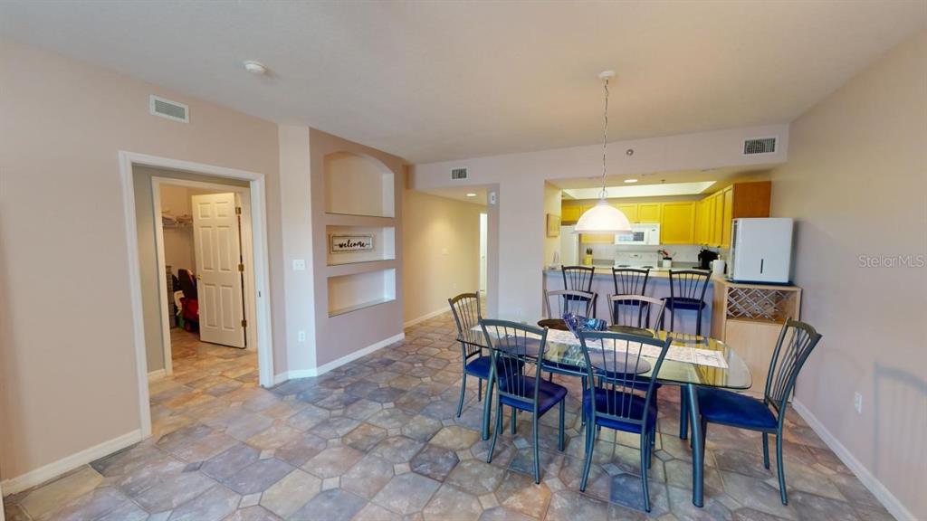 A dining area with a glass table and chairs sits adjacent to a kitchen counter — 5300 S ATLANTIC AVENUE UNIT 2-303, NEW SMYRNA BEACH, FL