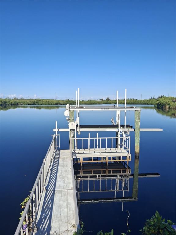 A wooden dock with a boat lift extends over calm water toward a mangrove shoreline — 150 MARTINIQUE ROAD UNIT 277, NORTH PORT, FL