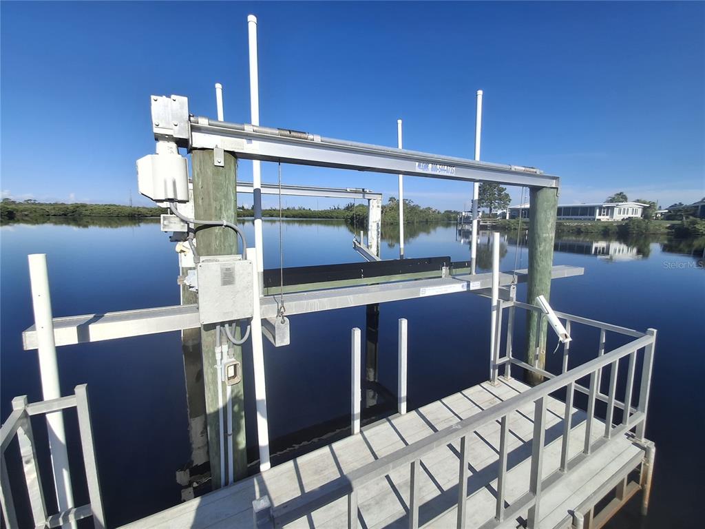 A boat lift stands over calm water next to a wooden dock — 150 MARTINIQUE ROAD UNIT 277, NORTH PORT, FL