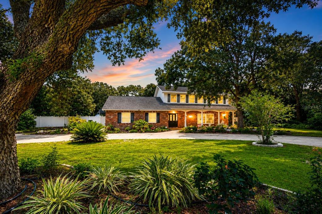 A two-story brick house with a covered front porch sits behind a large grassy lawn — 901 WOODVIEW DRIVE, BRANDON, FL