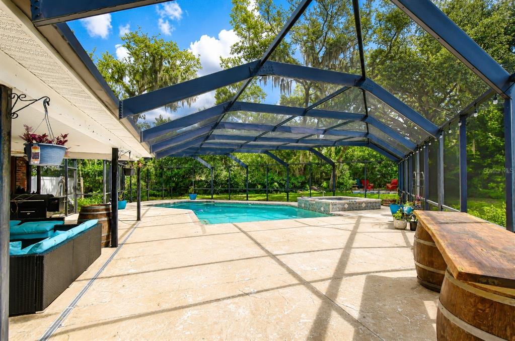 A screened-in pool patio with a hot tub, lounge furniture, and barrel-style tables — 901 WOODVIEW DRIVE, BRANDON, FL