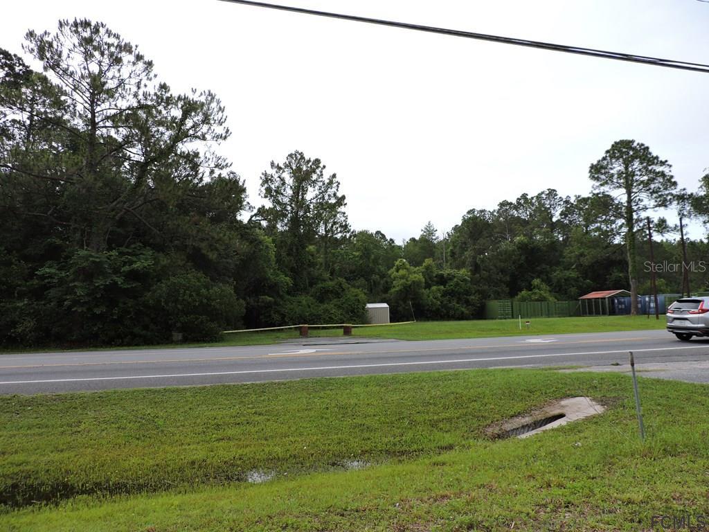 A grassy lot with a small shed sits across a road from a wooded area — 725 STATE ROAD, LAKE CITY, FL