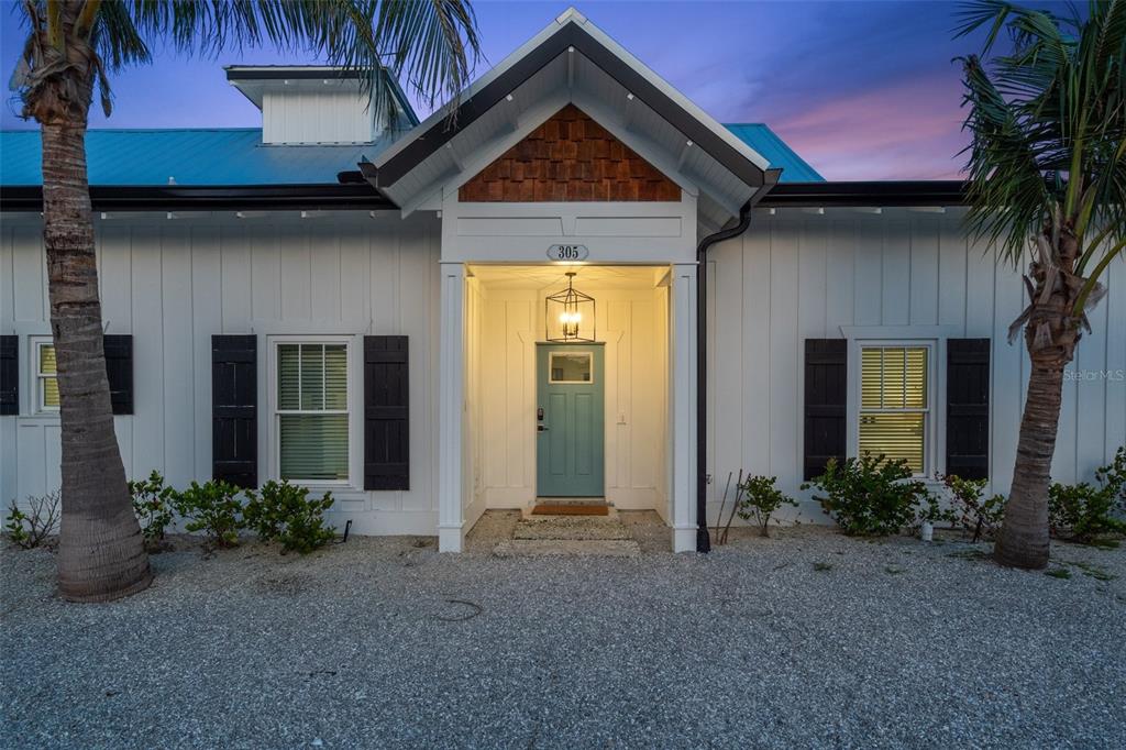 A white house with a teal front door, black shutters, and a metal roof — 305 73RD STREET, HOLMES BEACH, FL
