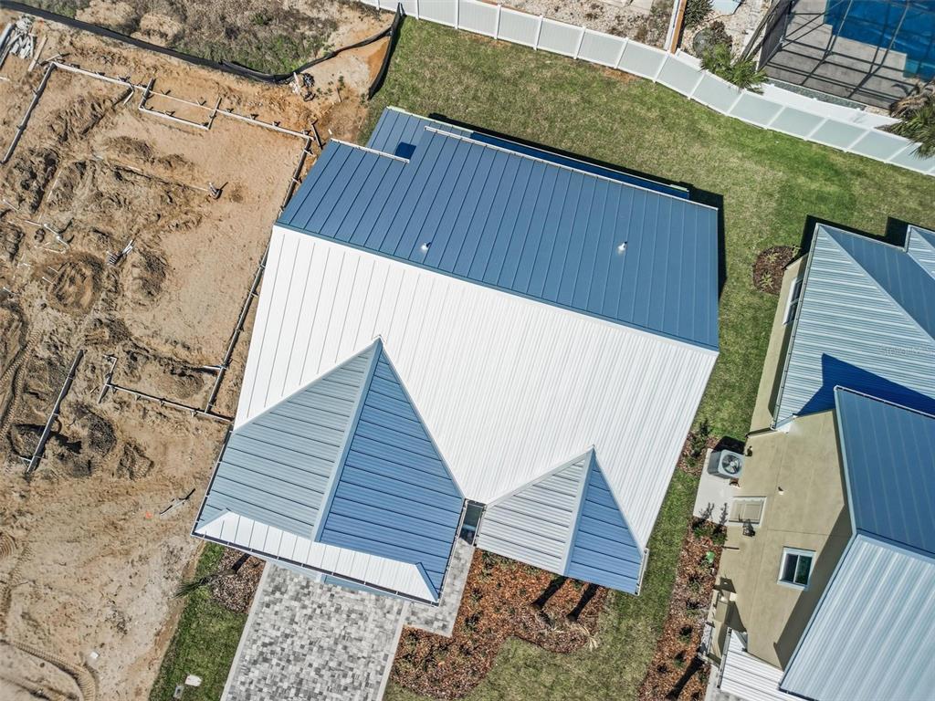 An aerial view shows a house with a multi-colored metal roof and a paved driveway — 116 BEACHVIEW DRIVE, ORMOND BY THE SEA, FL