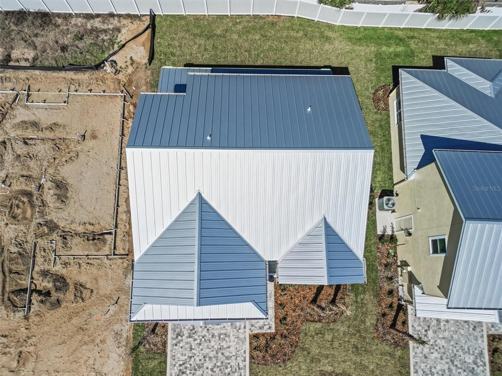 An aerial view shows the metal roof of a house next to a construction site — 116 BEACHVIEW DRIVE, ORMOND BY THE SEA, FL