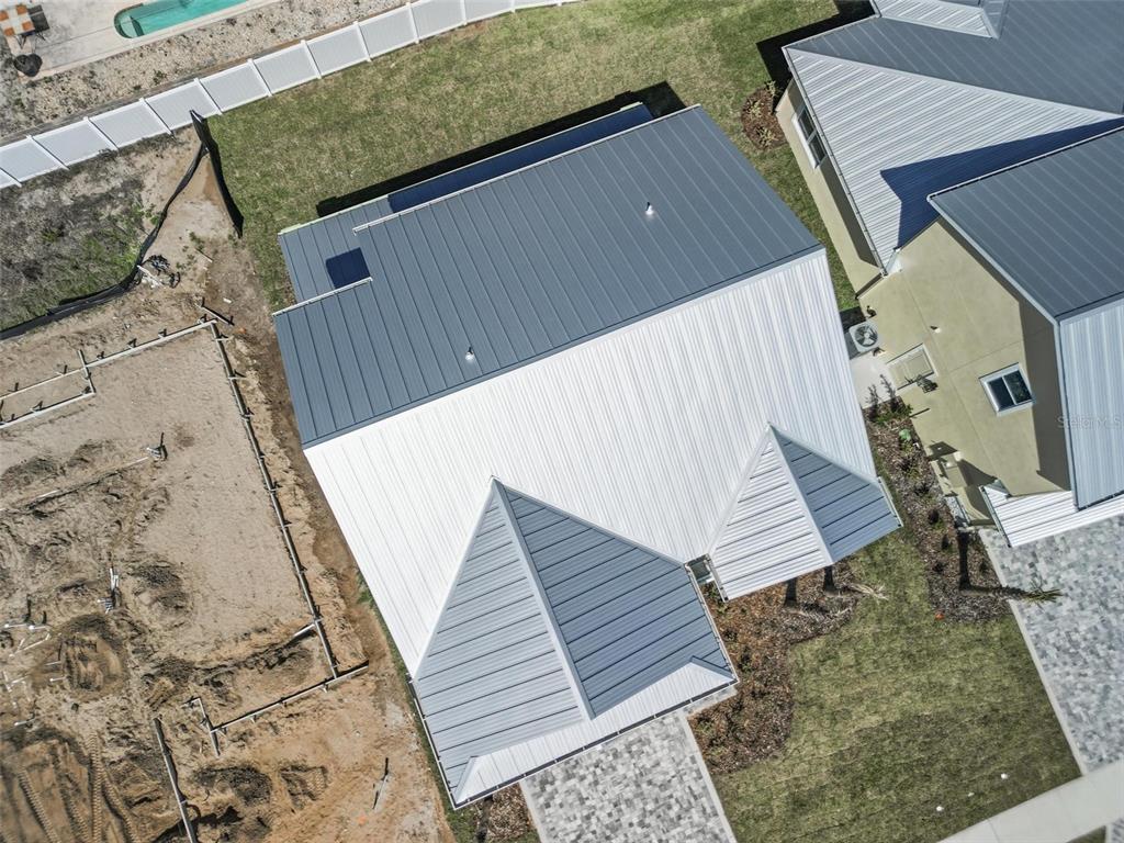 An aerial view shows a house with a metal roof and an adjacent construction site — 116 BEACHVIEW DRIVE, ORMOND BY THE SEA, FL