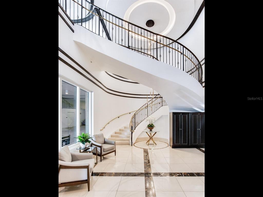 A grand foyer features a curved staircase, white tile flooring, and two armchairs — 3507 BAYSHORE BOULEVARD UNIT 1202, TAMPA, FL