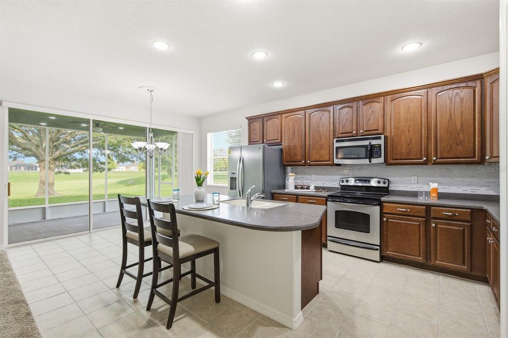 A kitchen with wood cabinets, stainless steel appliances, a center island, and a sliding glass door — 14830 POTTERTON CIRCLE, HUDSON, FL
