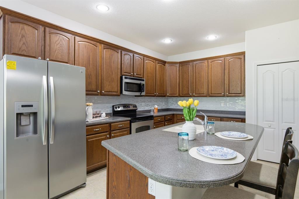 A kitchen with wood cabinets, stainless steel appliances, and a large gray island countertop — 14830 POTTERTON CIRCLE, HUDSON, FL