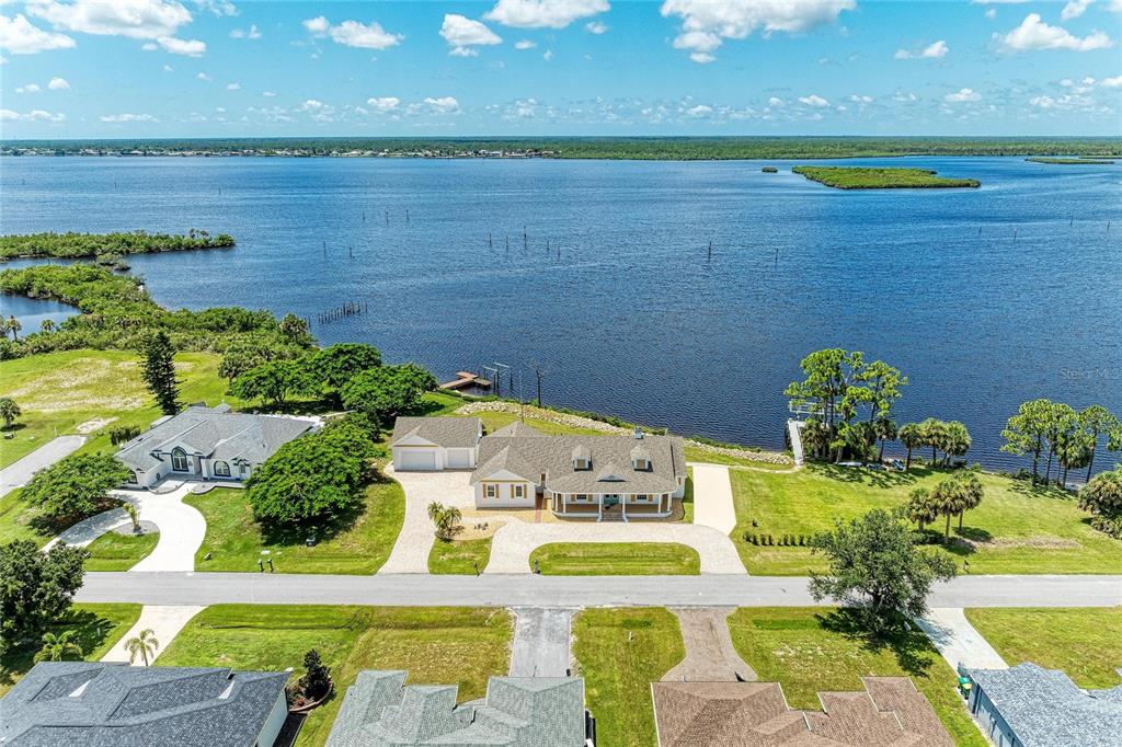 An aerial view shows a waterfront house with a large lawn and a private dock — 12323 LACKAWANNA LANE, PORT CHARLOTTE, FL