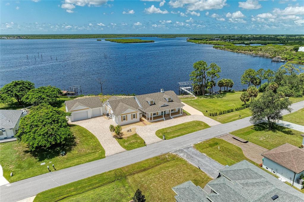 An aerial view shows a house with a multi-car garage situated along a waterfront — 12323 LACKAWANNA LANE, PORT CHARLOTTE, FL