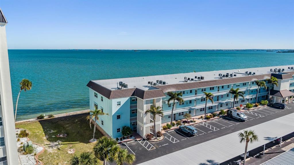 An aerial view shows a multi-story apartment building situated directly along a large body of water — 7 DUNOON PLACE UNIT 102, DUNEDIN, FL