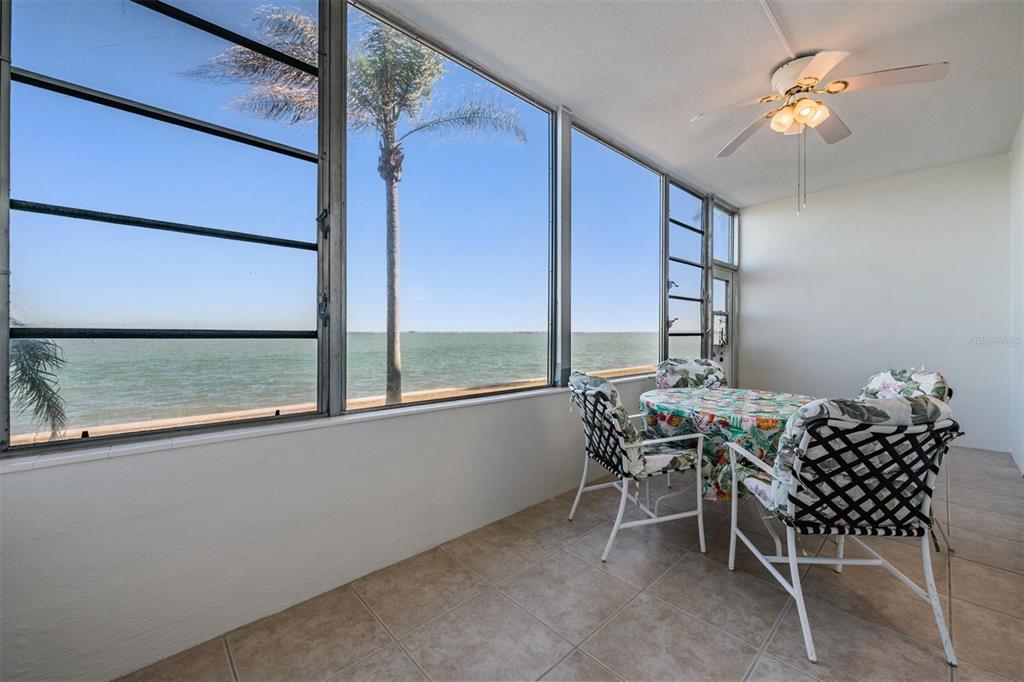 A sunroom with tile flooring, a dining set, and large windows overlooking the ocean — 7 DUNOON PLACE UNIT 102, DUNEDIN, FL