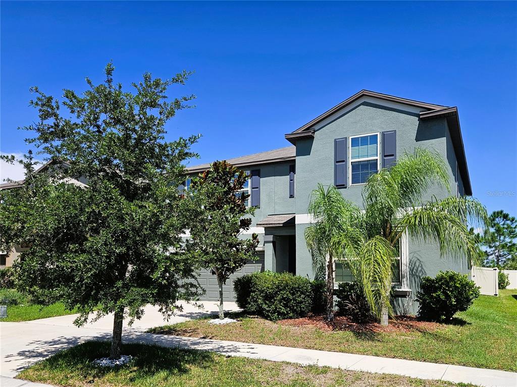 A two-story house with a light green exterior, a front yard, and a paved driveway — 6822 KING CREEK DRIVE, SUN CITY CENTER, FL