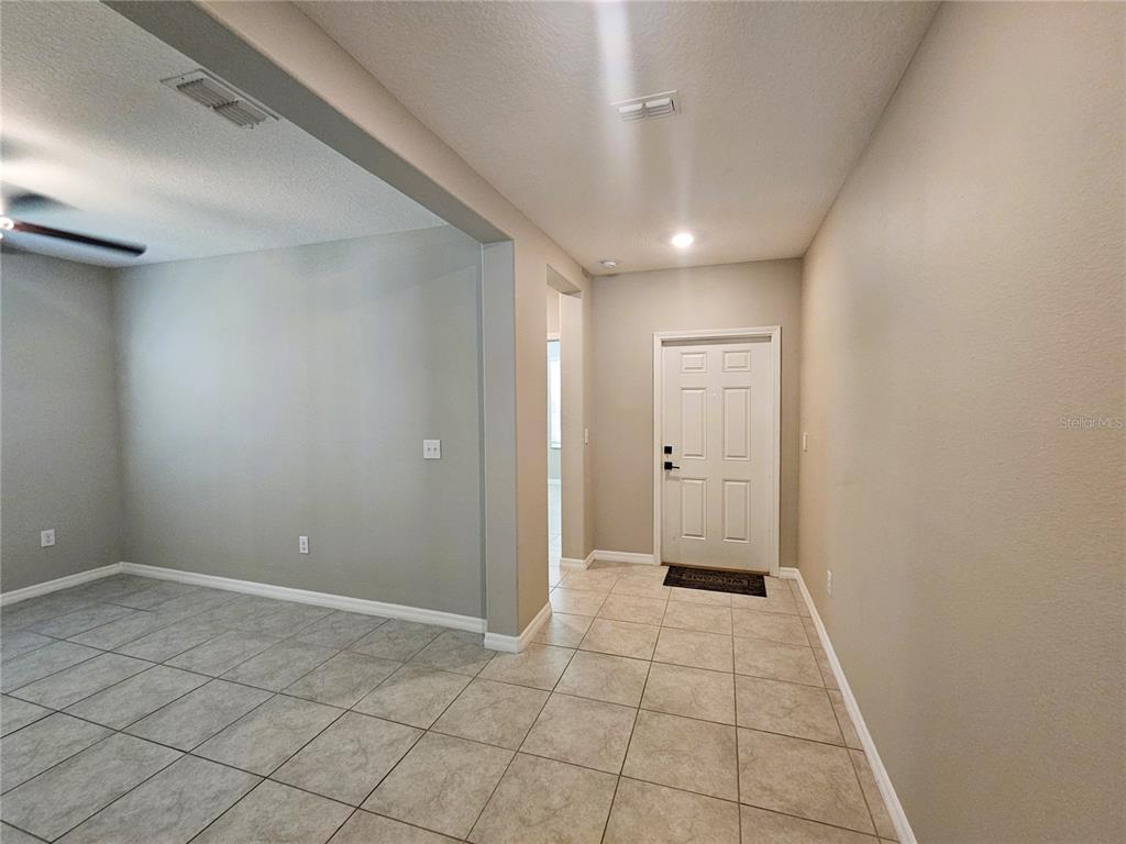 An entryway with tile flooring leads to a white front door and an adjacent room — 6822 KING CREEK DRIVE, SUN CITY CENTER, FL
