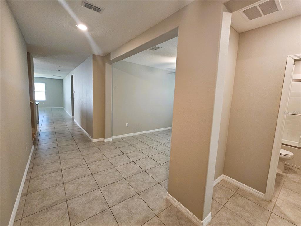 A tiled hallway leads to an open room with beige walls and a nearby bathroom — 6822 KING CREEK DRIVE, SUN CITY CENTER, FL